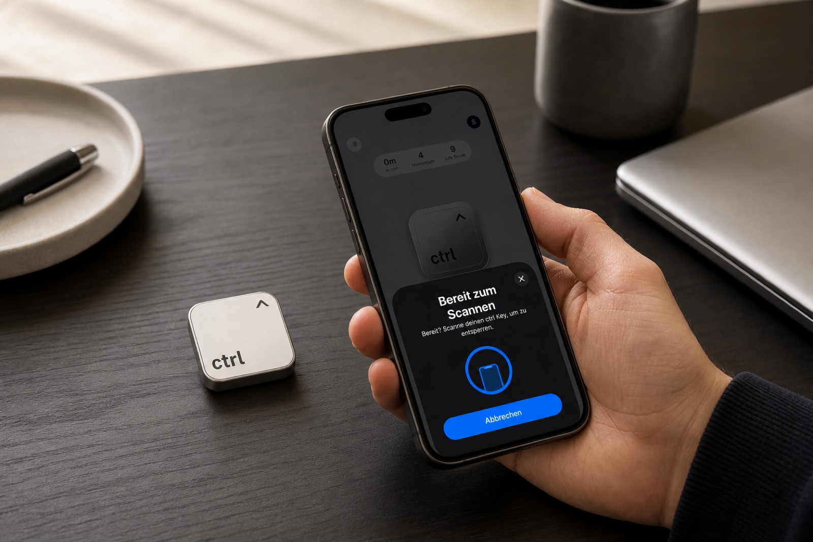 Eine Hand hält das Handy über den ctrl key auf dem Schreibtisch, die App zeigt Bereit zum Scannen